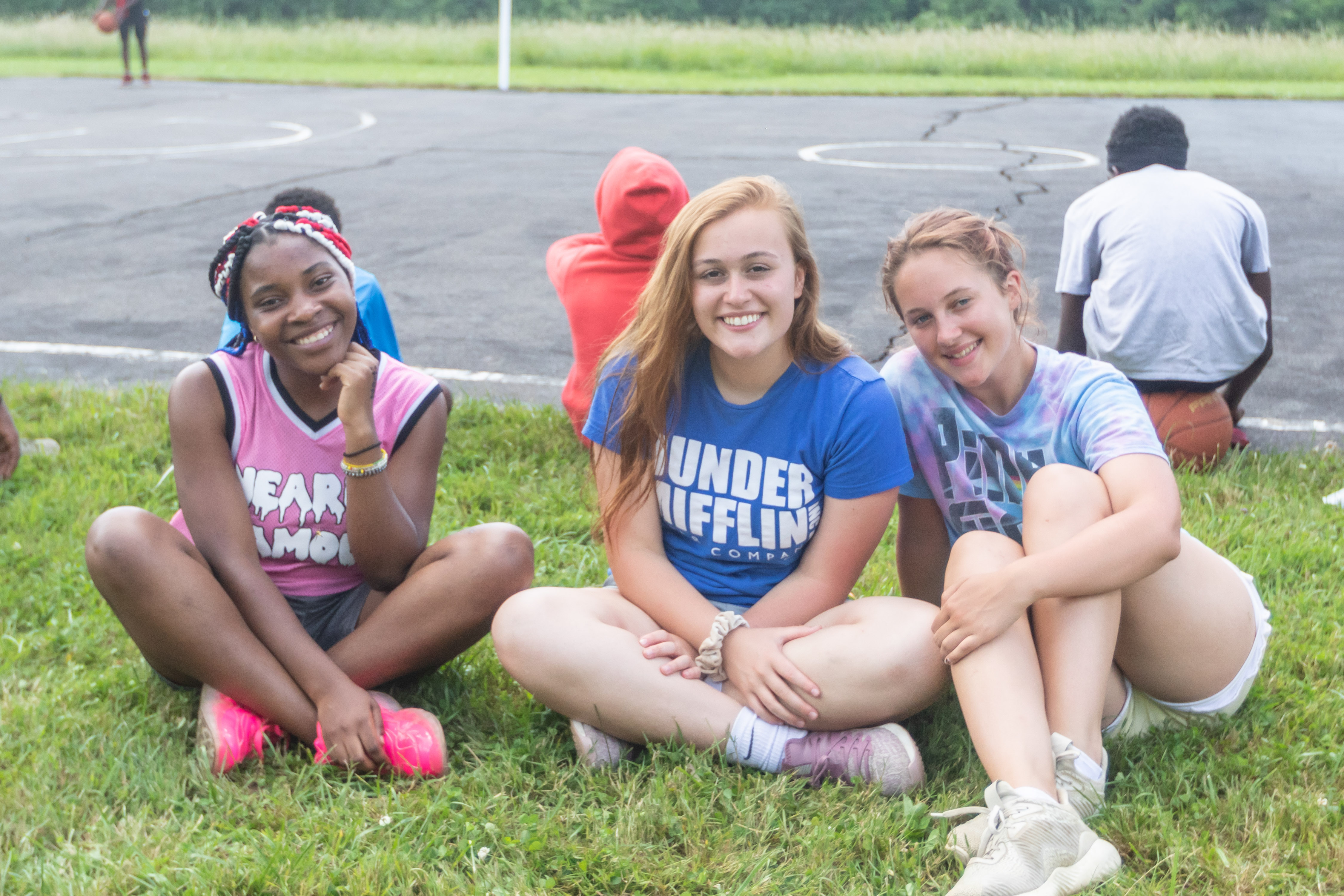 Girls sitting next to the basketball court